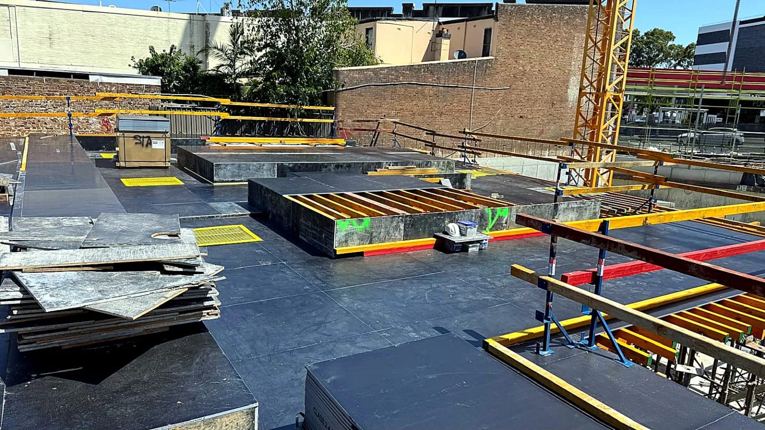 Black formwork sheets installed around slab openings and concrete upstands.