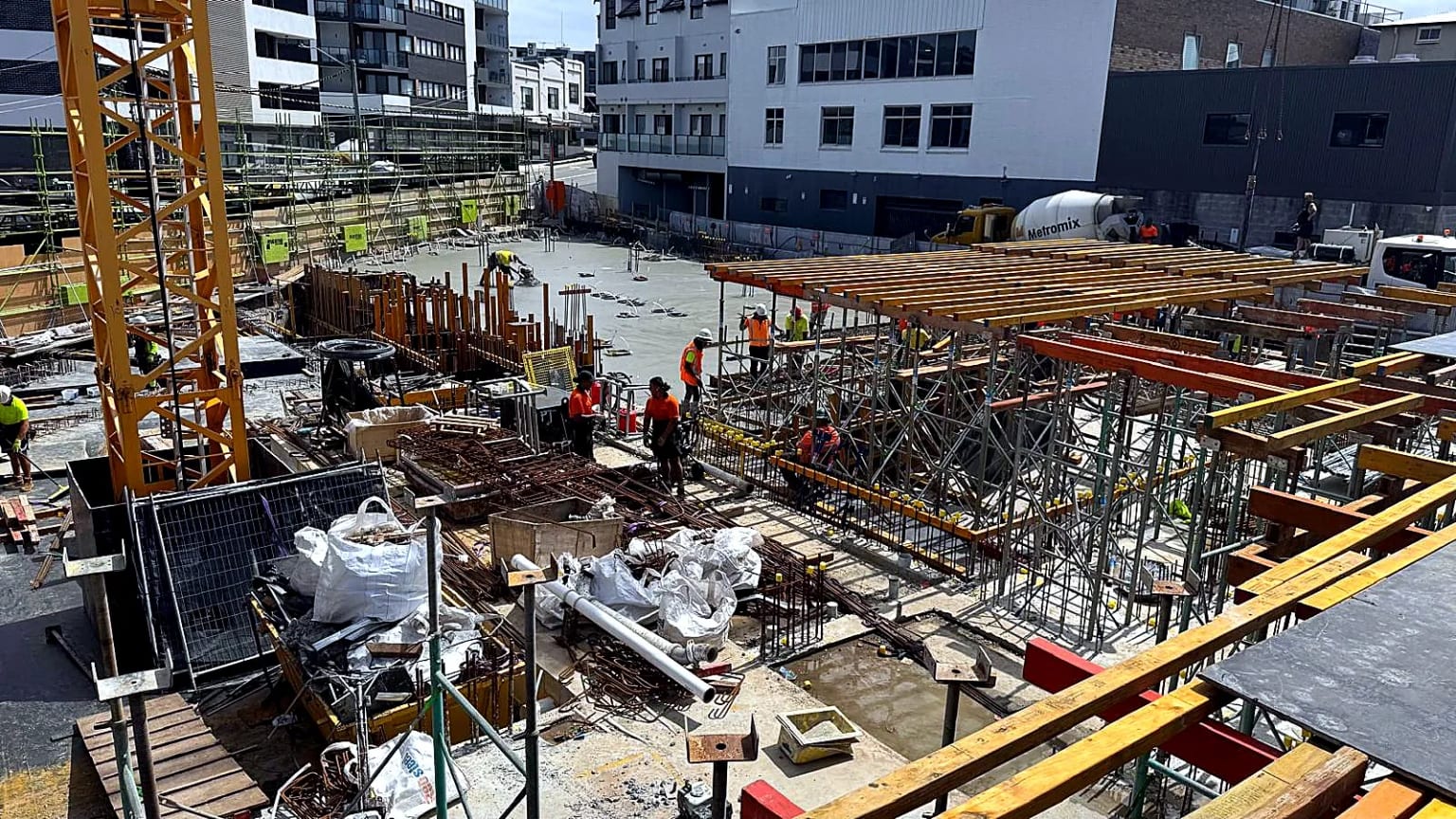 Site crew assembling shoring and formwork around a concrete work area.