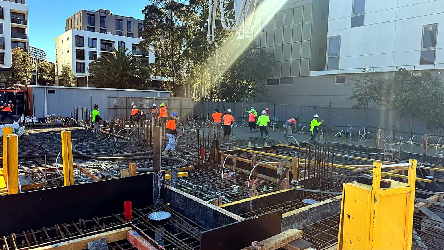 Site crew placing and finishing concrete between reinforced sections.