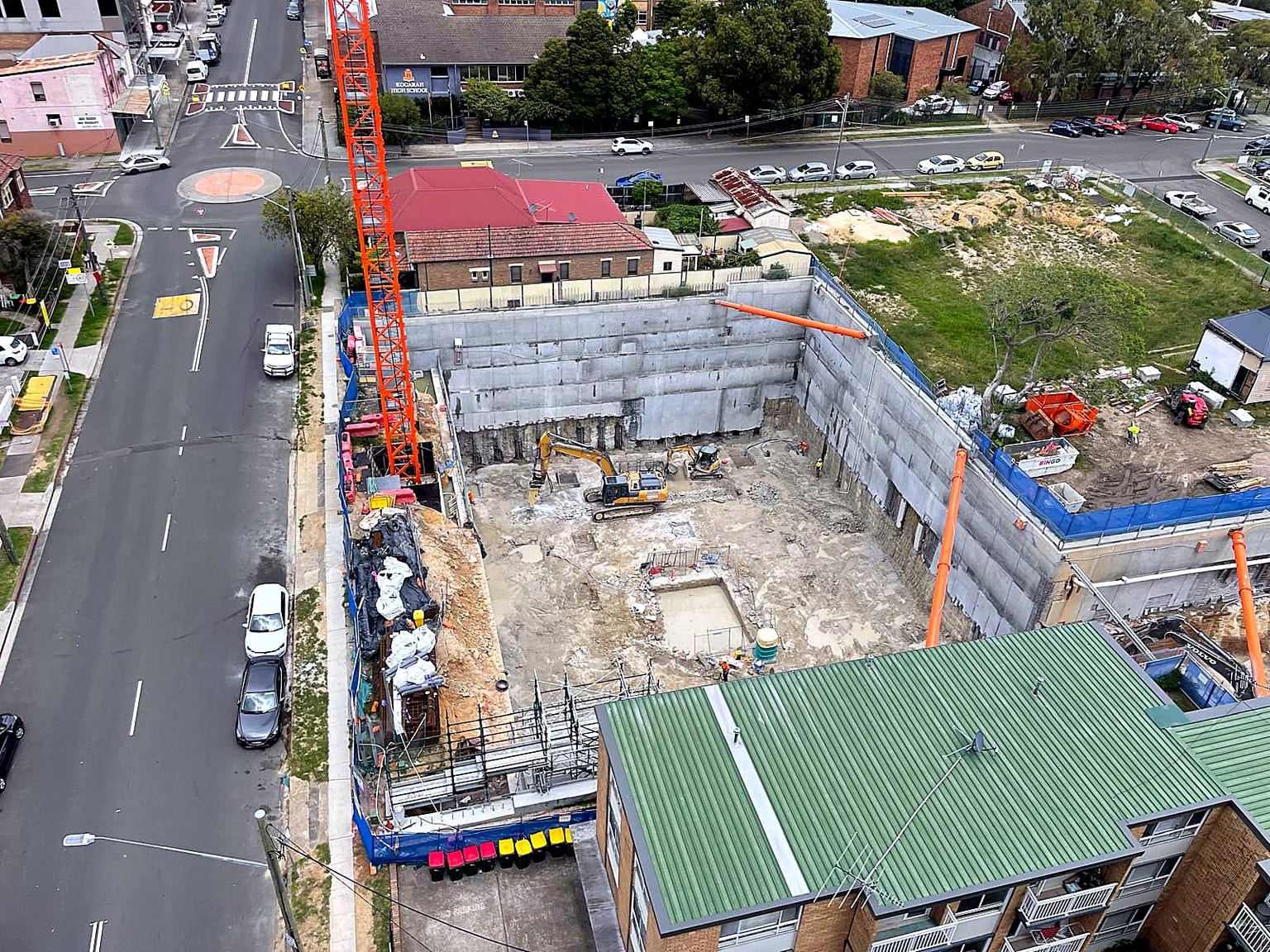 Aerial view of a deep shored excavation with plant working on the basement level.