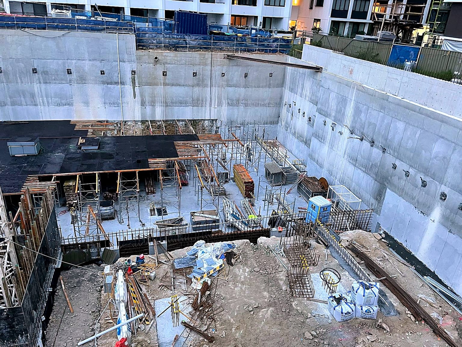 Basement slab formwork and shoring progressing against concrete retaining walls.