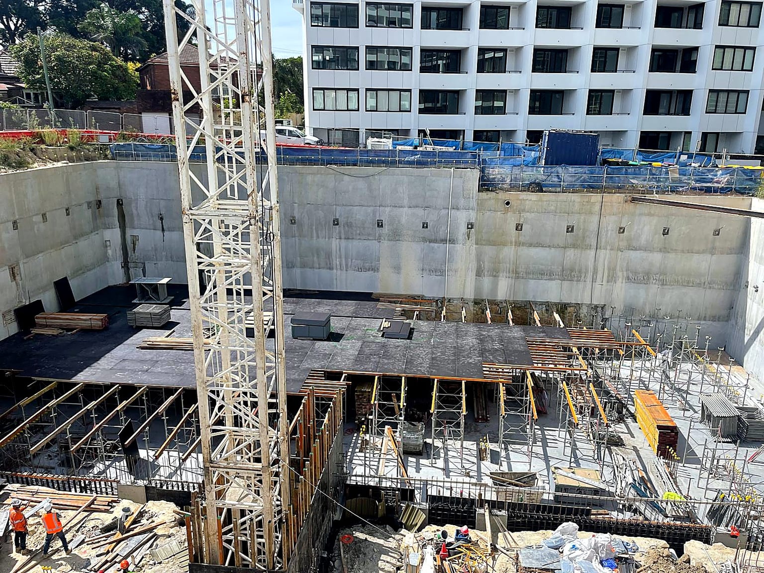 Basement slab formwork and shoring arranged around a tower crane.