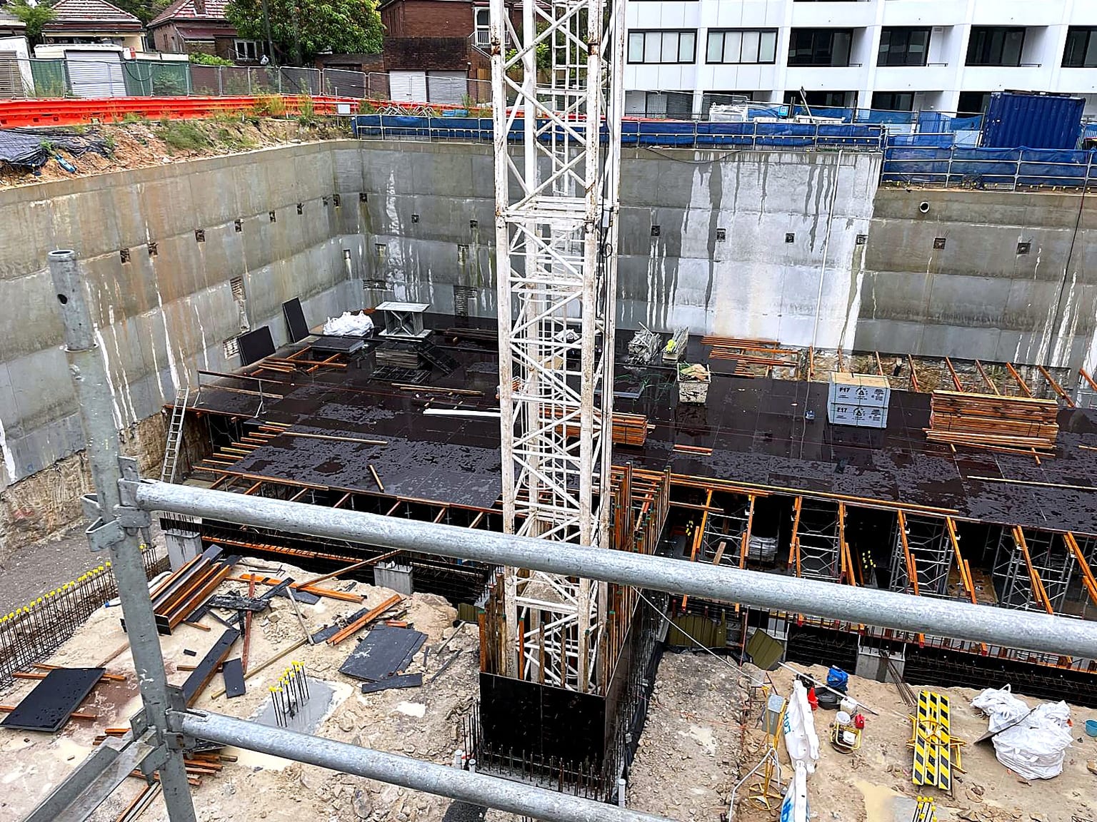 Aerial view of deck formwork and shoring progressing around a tower crane.