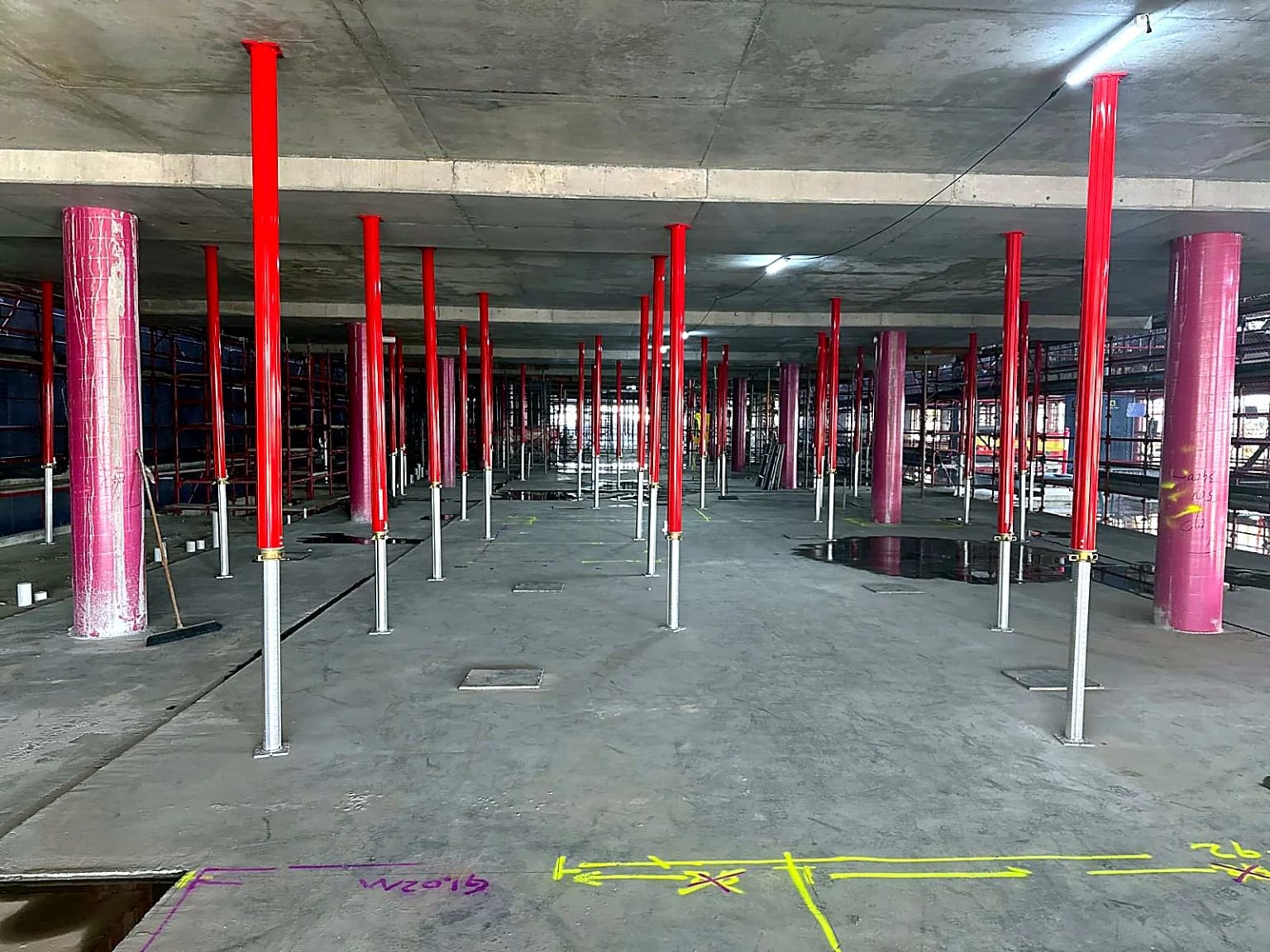 Temporary props supporting a concrete slab between round columns.