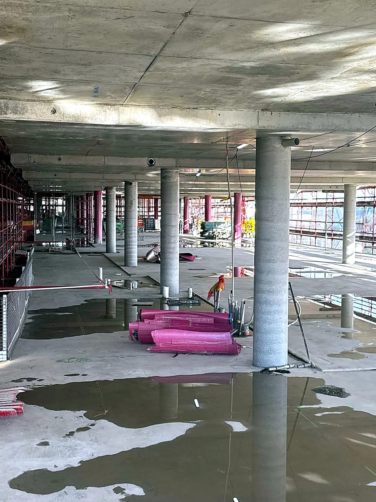 Concrete columns and slab viewed across an open floor under construction.
