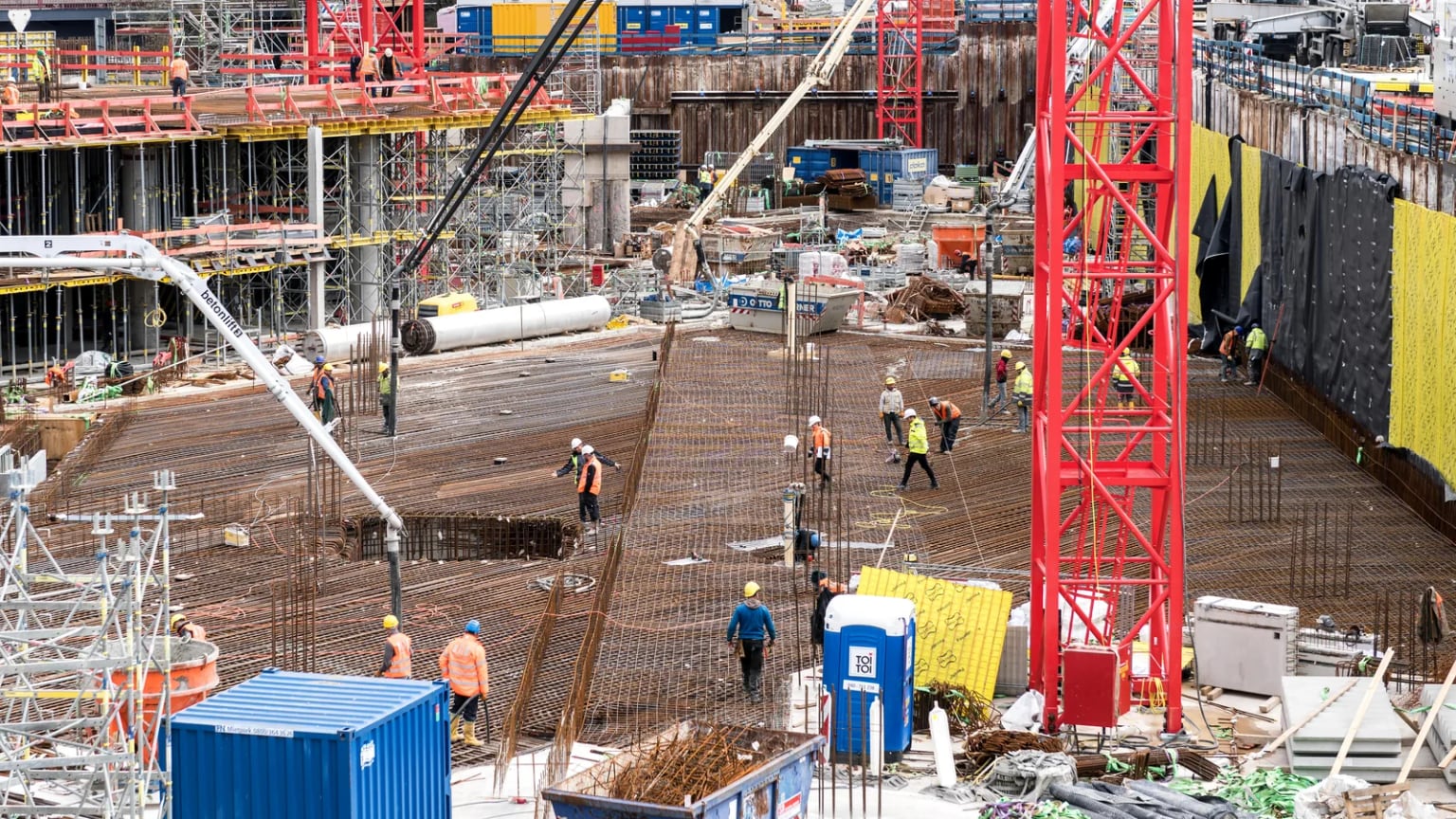 Construction crew working across dense slab reinforcement on a large concrete building site.
