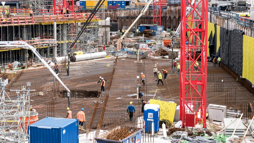 Construction crew working across dense slab reinforcement on a large concrete building site.