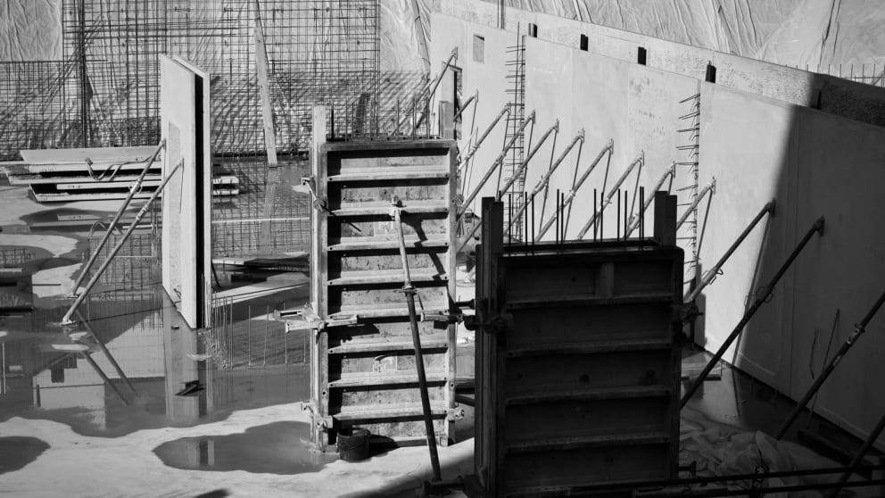 Wall and column formwork braced beside reinforcement cages on a concrete slab.