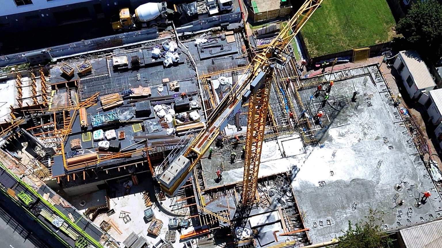 Aerial view of a tower crane over slab reinforcement, formwork and a concrete pour.