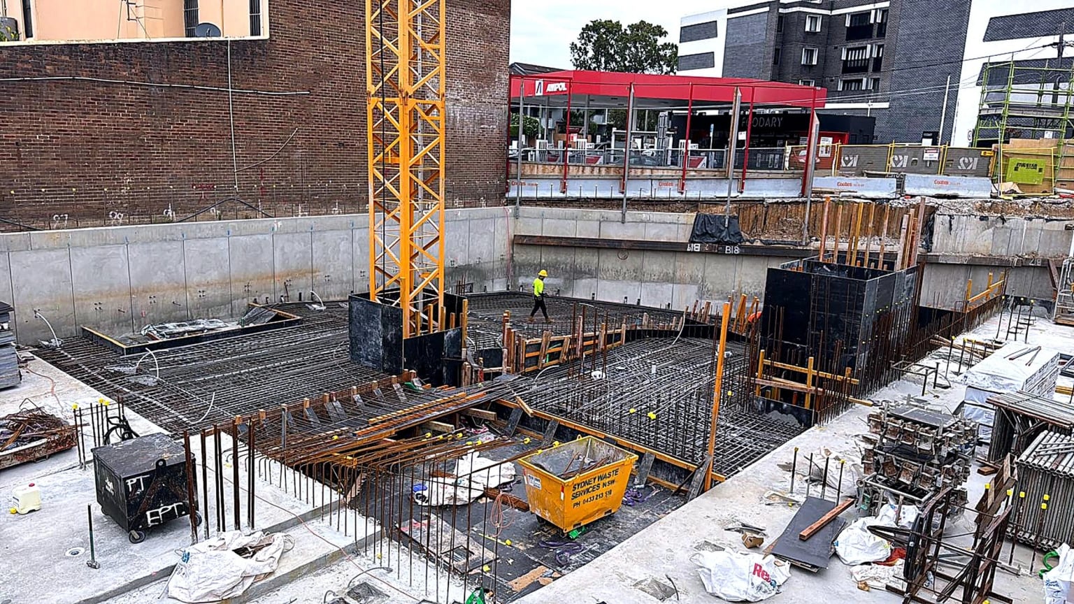 Basement slab reinforcement and wall formwork arranged around a tower crane.