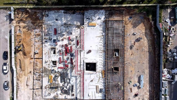 Top-down aerial view of concrete slabs and reinforcement across a multi-building construction site.