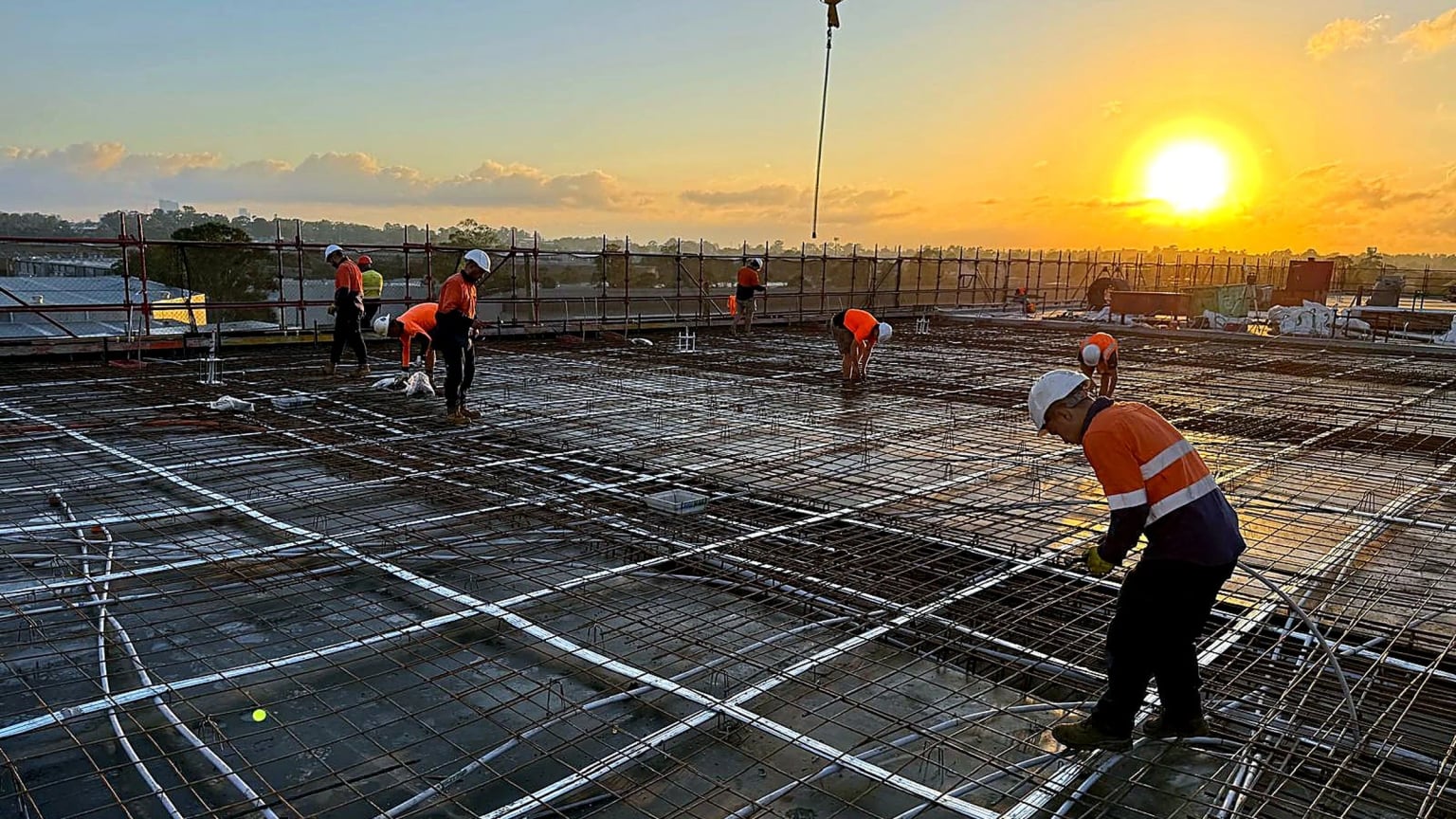 Site crew tying slab reinforcement at sunset on the Yennora project.
