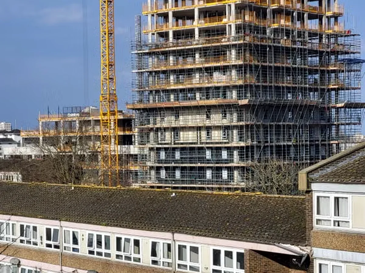 Multi-storey concrete frame under construction beside a tower crane.