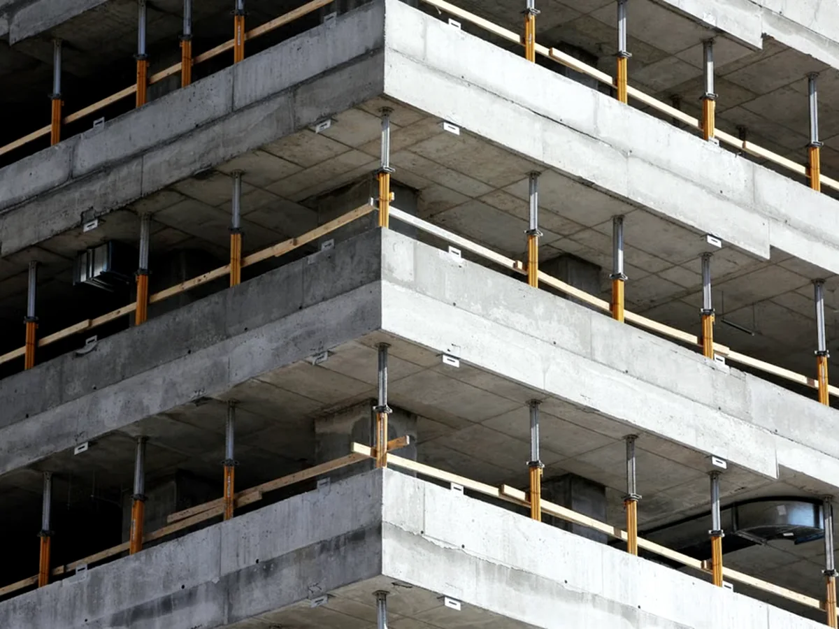 Exposed reinforced concrete floor plates with temporary edge protection on a multi-storey structure.