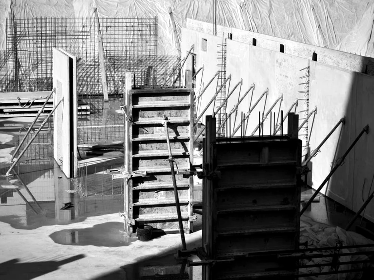 Wall and column formwork braced beside reinforcement cages on a concrete slab.