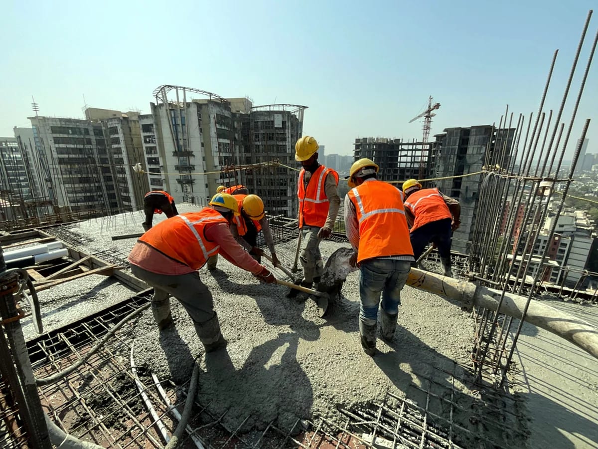 Construction crew placing concrete around reinforcement on an elevated slab.